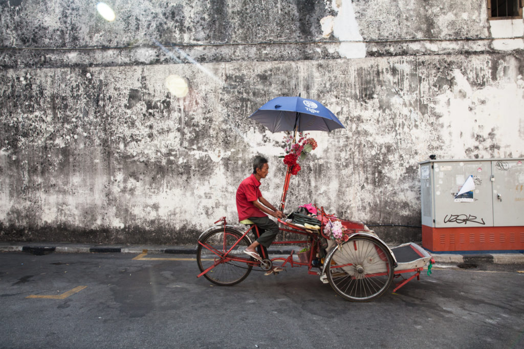 Cycle rickshaw rides down the street in George Town