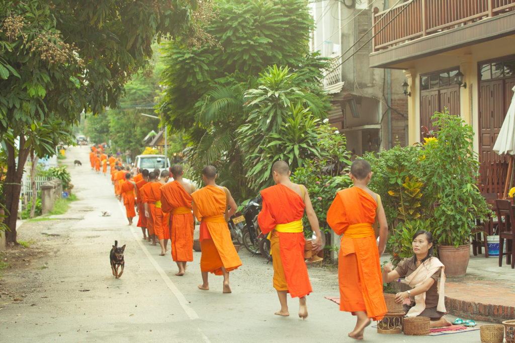 A procession of monks at a street of Luang Prabang, Laos