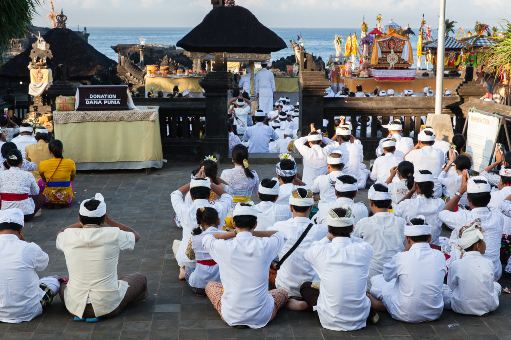 Balinese people pray in the temple during religious ceremony, Tanah Lot, Bali, Indonesia